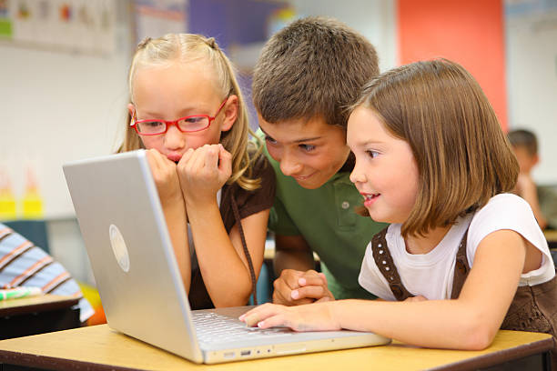 Elementary school students look at laptop computer  elementary school building photos stock pictures, royalty-free photos & images
