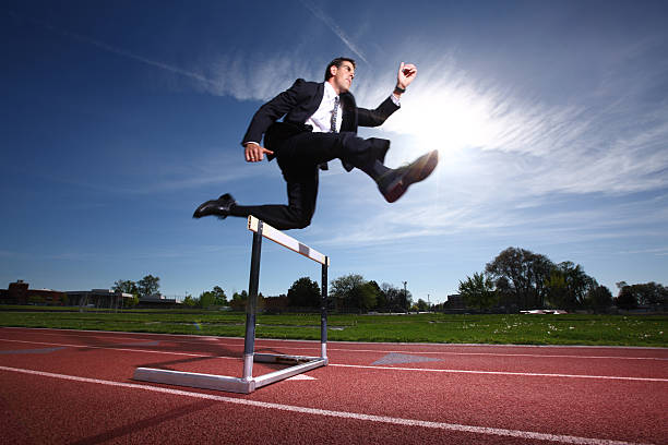 homme d'affaires sauter over hurdle - hurdling photos et images de collection