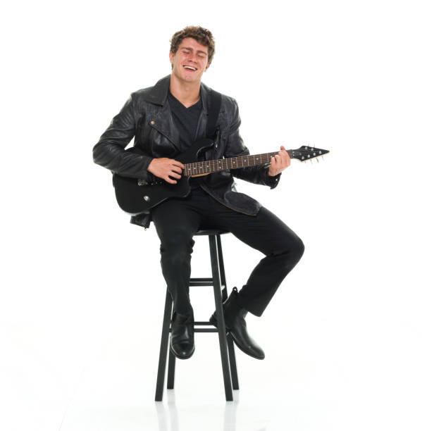 istock Attractive man playing electric guitar seated on stool 916985774