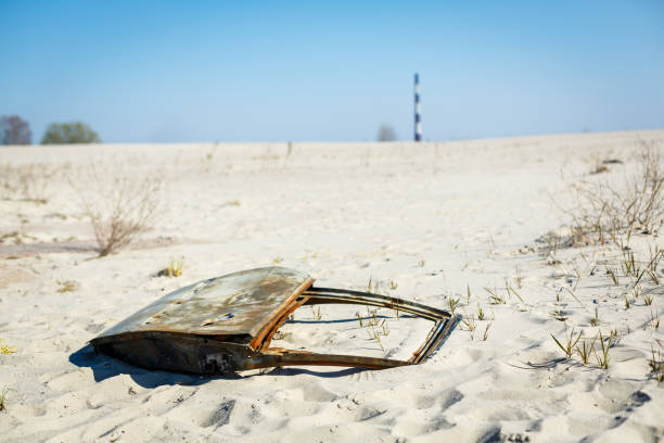 istock Rusted car door left as a trash or waste in a sandy dune 916986460