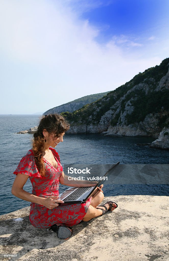 Giovane ragazza con Lap-top sulla scogliera Brsec-Croazia - Foto stock royalty-free di Acqua