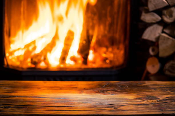 istock Old wooden table and fireplace with warm fire. 917008424