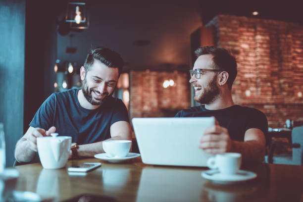 istock Two Smiling  Male Freelancers Drinking Coffee and Video Conferencing In Coffee Restaurant 917011374