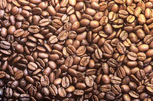 Texture of roasted coffee beans with contrasting dramatic light effect.