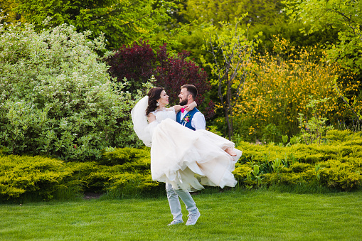 Happy couple outdoors, barefoot woman in man hands during their wedding day. Wedding day.