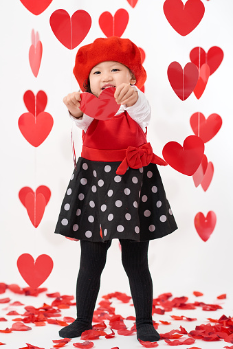 Cute Asian baby girl with hearts and rose pedals on Valentine's Day