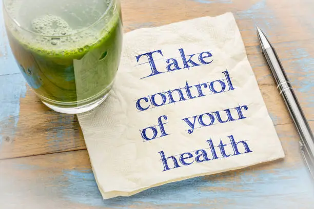 Take control of your health advice - handwriting on a napkin with a glass of fresh, green, vegetable juice