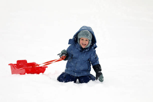 istock Little boy tobogganing and playing with snow 917024170