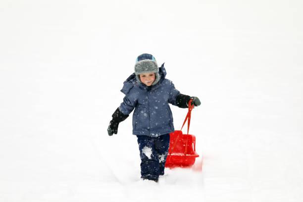 istock Little boy tobogganing and playing with snow 917024174