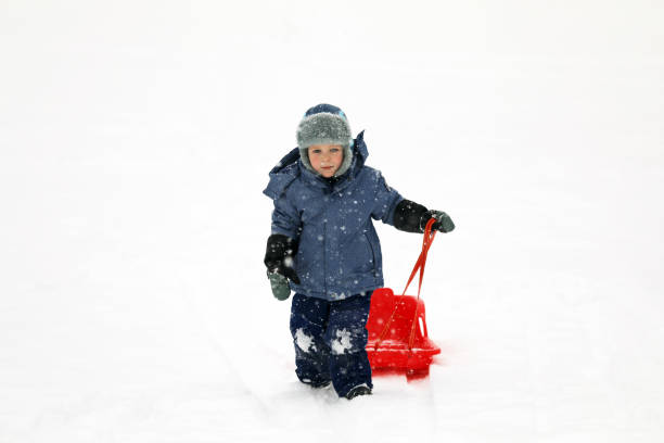 istock Little boy tobogganing and playing with snow 917024178