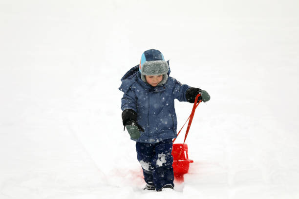 istock Little boy tobogganing and playing with snow 917024184