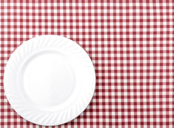istock White Plate on Red and White checkered Fabric Tablecloth Background. 917027486