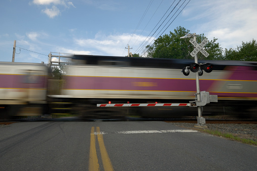 A speeding train going thru a railway crossing.