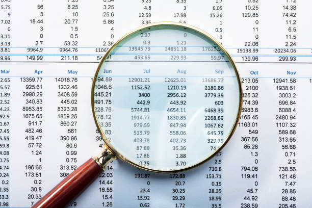 увеличительное стекло в финансовом отчете - финансовые цифры стоковые фото и изображения