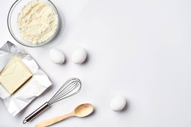 istock Preparation of the dough. Ingredients for the dough - flour, butter, eggs and various tools. On white background. Free space for text . Top view 917039992