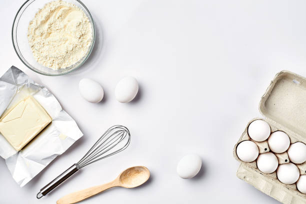 preparation of the dough. ingredients for the dough - flour, butter, eggs and various tools. on white background. free space for text . top view - baking flour ingredient animal egg imagens e fotografias de stock