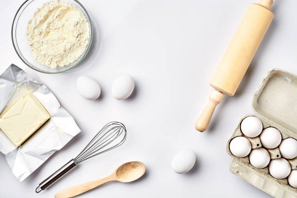 istock Objects and ingredients for baking, plastic molds for cookies on a white background. Flour, eggs, rolling pin, whisk, milk, butter, cream. Top view, space for text 917040180