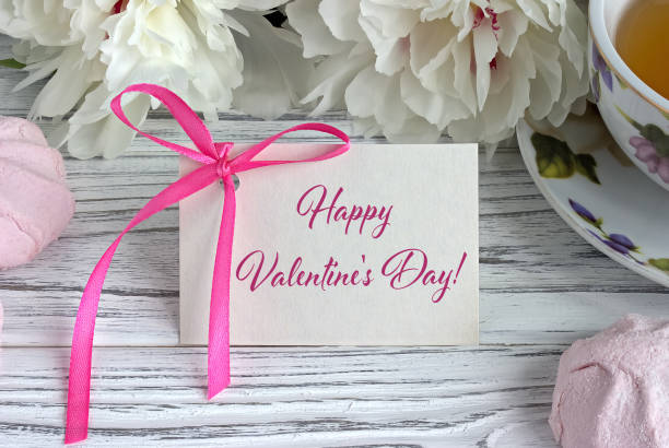 istock Valentines day greeting card with white peonies tea cup marshmellow and lettering. 917052876