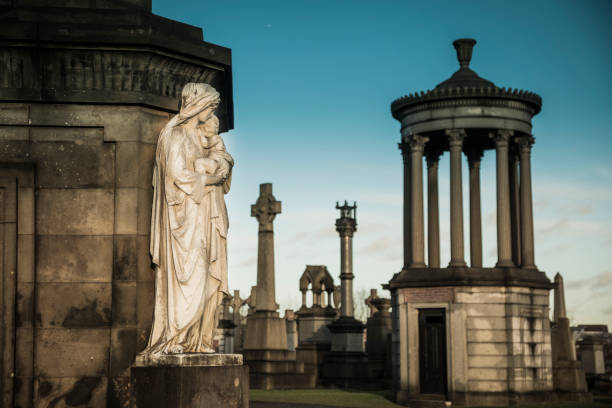 Victorian tombs in Glasgow's Necropolis cemetery in the evening light. The tomb with the statue was designed in 1845 in a Graeco-Egyptian style.