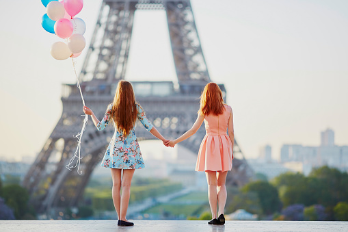 Two girls with bunch of balloons near Eiffel tower