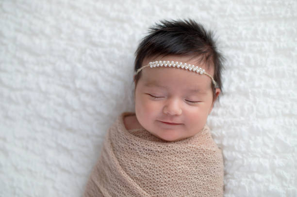 ベージュのおくるみに包まれた赤ちゃんの笑顔 - baby people headband portrait ストックフォトと画像