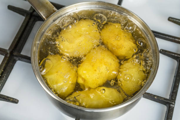 未処理のジャガイモは、ガスコンロに鍋に沸騰します。 - young potatoes ストックフォトと画像