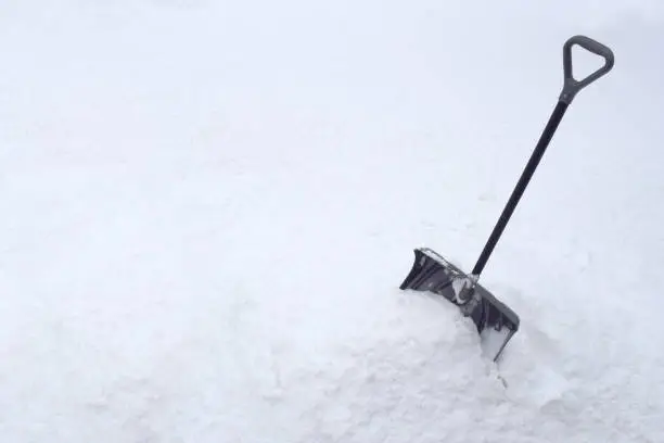 Snow Shovel in Snow Pile During Cold Winter White Snowstorm