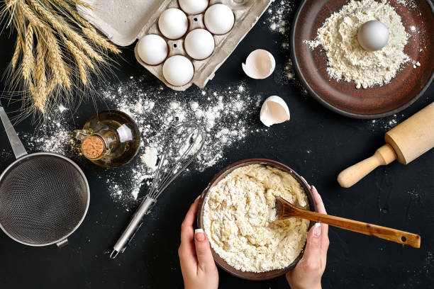 istock Female hands making/ mixing dough in brown bowl on black table, baking preparation close-up 917063564