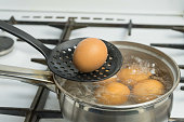 Chicken eggs boil in water. Pan with the product on a gas stove.