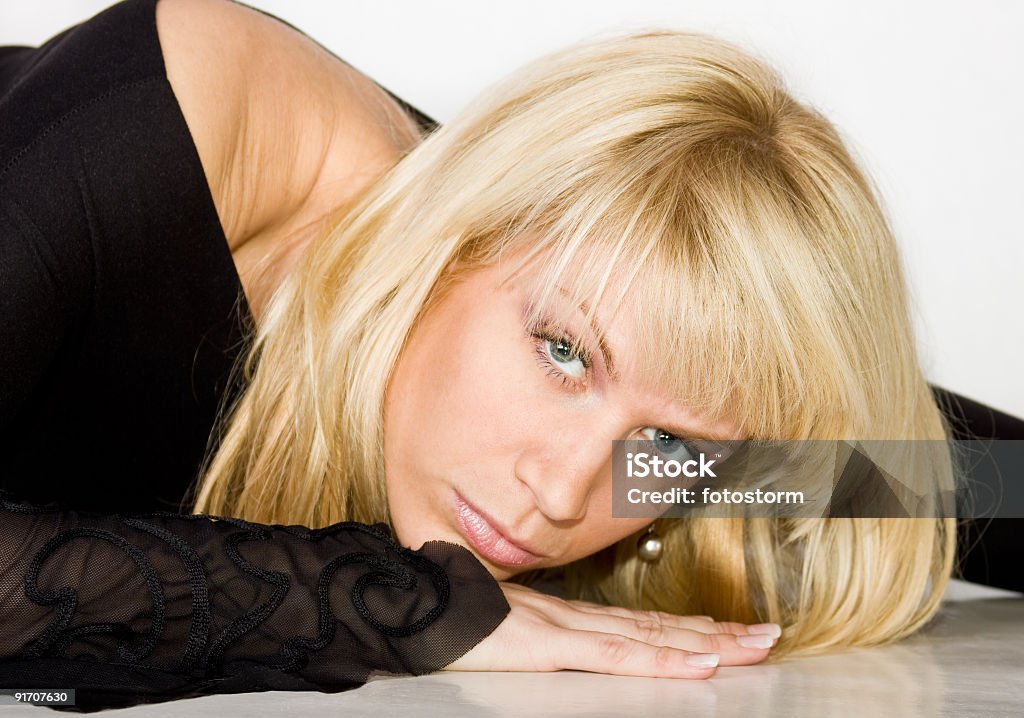Portrait of a lovely blond woman Young lovely blond woman lying on her hands and looking toward camera. Adult Stock Photo