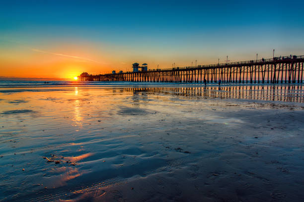 California Pier at Sunset The pier in Oceanside, California located in northern San Diego County as the sun sets behind it. low tide stock pictures, royalty-free photos & images