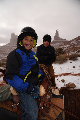 Father and son enjoy horse riding in winter in Utah