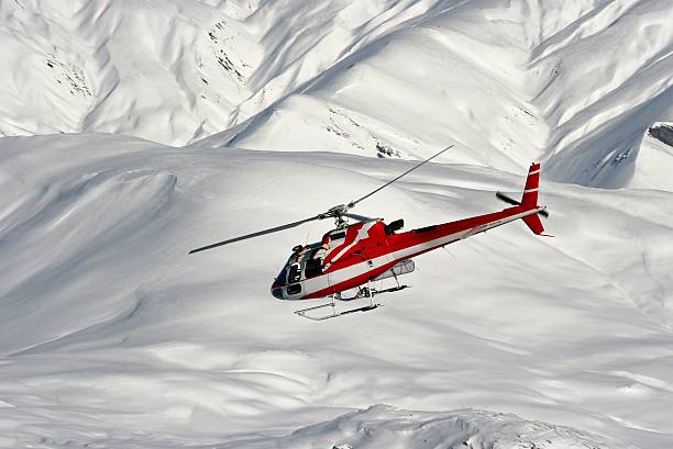 istock A red and white helicopter flying over snowy mountains  91709456
