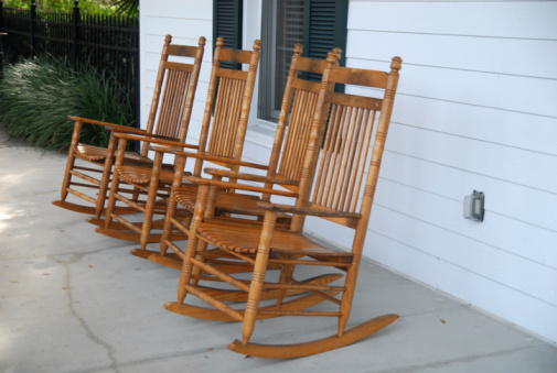 A patio with four rocking chairs in the old south.