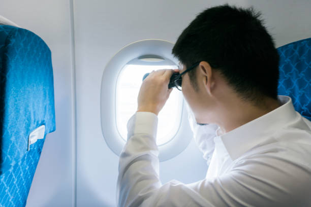 istock Businessman looking with binoculars in airplane 917107514