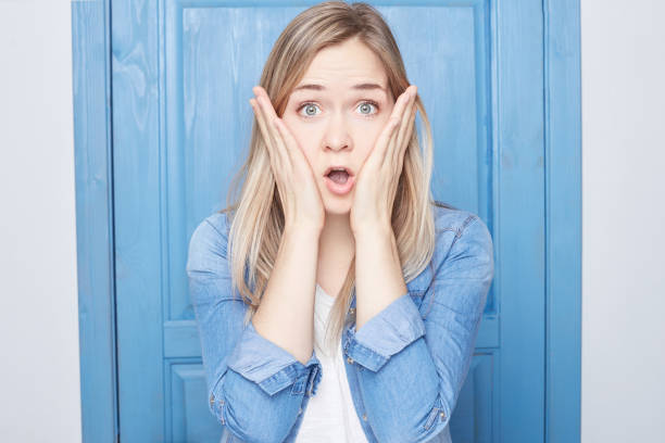 istock Screams in terror, keeps hands on head, mouth opened wide 917117216
