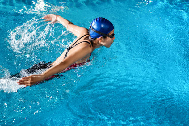 Swimmers are swimming "butterfly" poolside at night. Swimmers are swimming "butterfly" poolside at night. competition group stock pictures, royalty-free photos & images