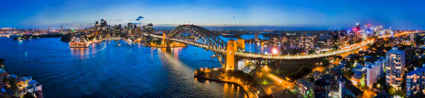 D Sy Kirrib Dark CBD Pan Dark Sydney city CBD landmarks around Sydney Harbour connected by Sydney Harbour bridge and bright cahill expressway illuminated and reflecting in water. sydney harbor stock pictures, royalty-free photos & images