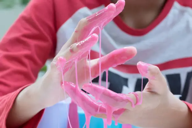 Hand Holding Homemade Plaything Called Slime, Teenager having fun and being creative homemade Toy, Selective focus on Slime.