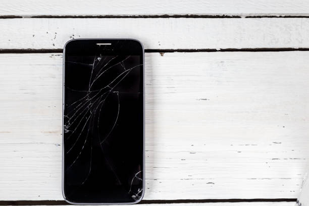 istock Broken screen of the modern smartphone, on a white wooden table. Top view 917133190