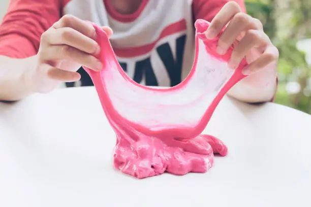 Hand Holding Homemade Plaything Called Slime, Teenager having fun and being creative homemade Toy, Selective focus on Slime.