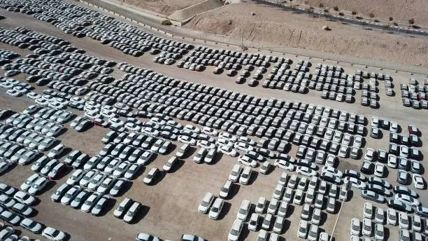 New cars covered in protective white sheets parked in a holding platform - Aerial image