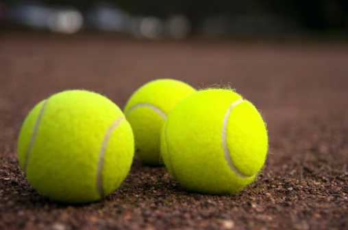 close picture of three tennis balls in a hard court