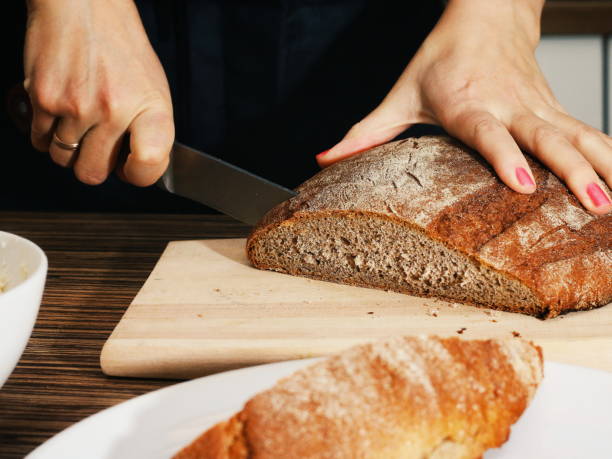istock Female hands Cutting dark Bread on a wooden board 917142622