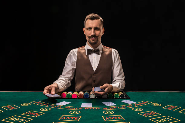 テーブルのカジノでギャンブルの背後にあるディーラー - casino worker ストックフォトと��画像