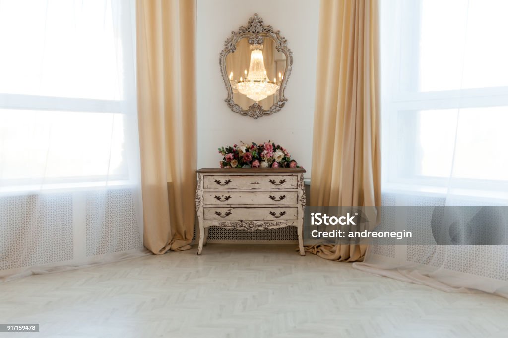 White chest of drawers in white interior White chest of drawers in white interior with two window with sunlight Antique Stock Photo