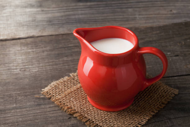 istock Milk in glass pitcher on white background wooden table 917162452