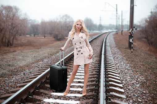 Rear view of woman with luggage walking on rail road