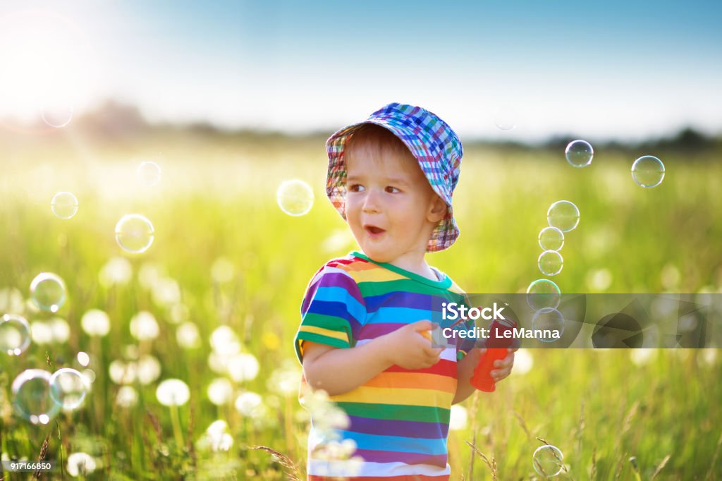 Niño de pie en la hierba en la fieald con dientes de León - Foto de stock de Bebé libre de derechos