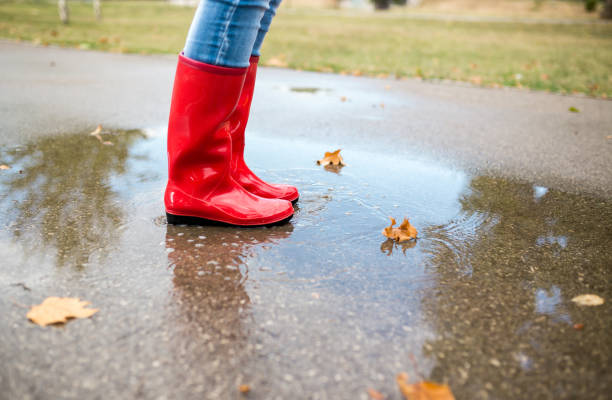 istock Rubber boots are jumping into a big puddle with splash. 917170052